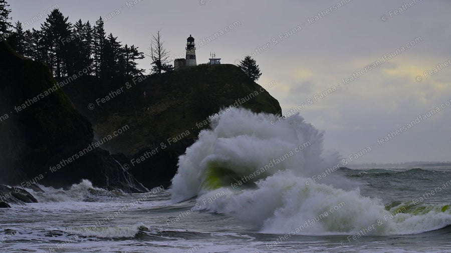 A large wave bursting against a headland below a cliff-top lighthouse.